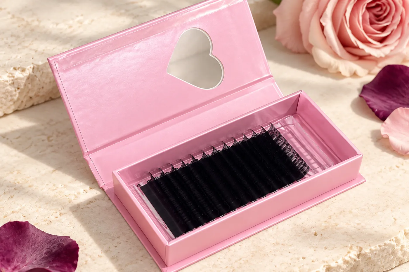 Open pink carton containing rows of black individual lash extensions
